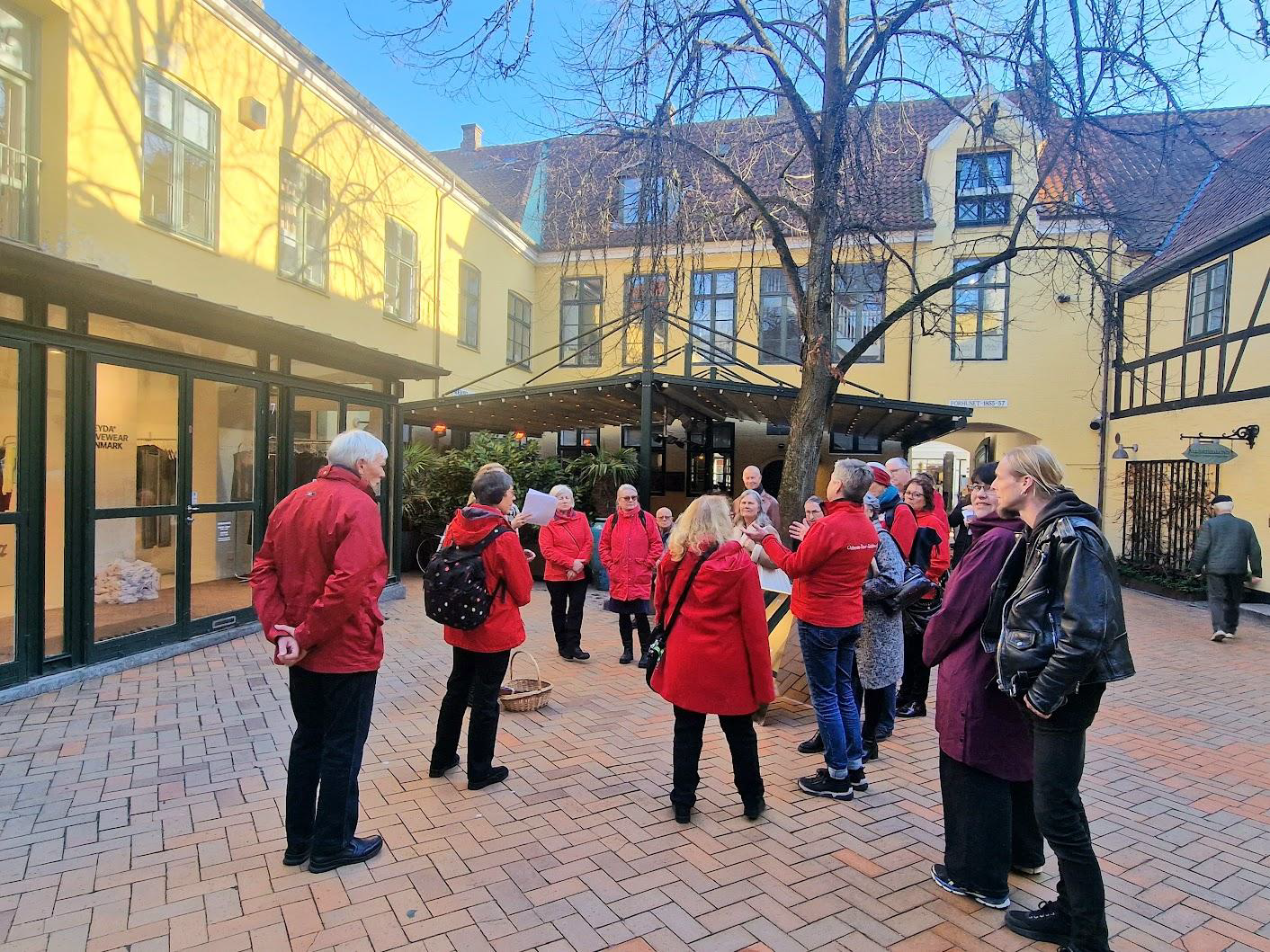 A group on a tour of Brandt Textile Factory with the red-clad guides from Odense Tour Guides